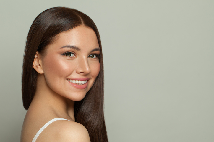 Pretty model woman with clear skin and long healthy straight hair. Skincare and facial treatment concept