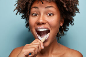 Afro American teen girl opens mouth widely brushes teeth