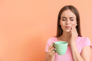 Young,Woman,With,Sensitive,Teeth,And,Cup,Of,Hot,Coffee
