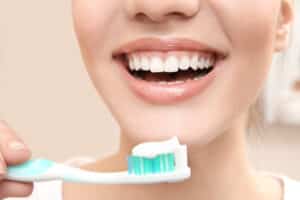 Woman with gummy smile with toothbrush considering gum recontouring in Milwaukee, WI