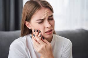 Woman holding her mouth in pain from tooth abscess in Milwaukee, WI