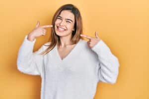 Woman smiling pointing to her teeth after a dental cleaning in Milwaukee, WI