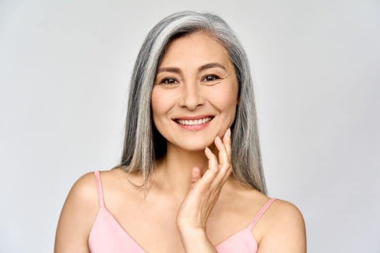 Woman smiling confidently with fixed dentures in Milwaukee, WI