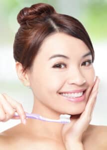 Woman with complete smile about to brush her teeth after root canal in Milwaukee