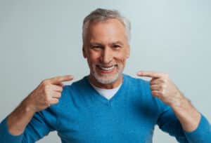 Man smiling and pointing to his dentures in Milwaukee, WI