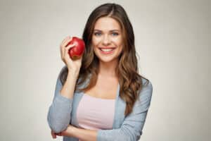 Woman about to eat an apple after full mouth reconstruction in Milwaukee, WI