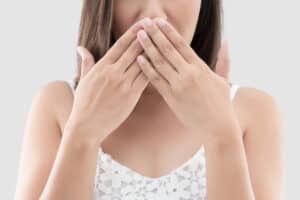 Woman covering her mouth due to bad breath from possible gum disease in Milwaukee