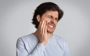 Man holding his jaw in pain needing restorative dentistry in Milwaukee, WI